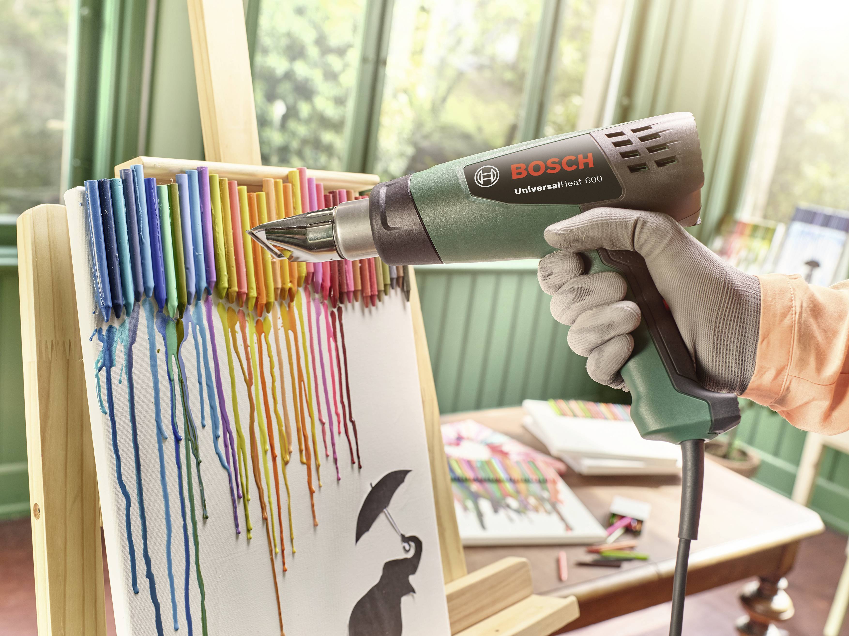 A Bosch hot air blower melts wax crayons over a canvas, allowing rainbow colours to run down.