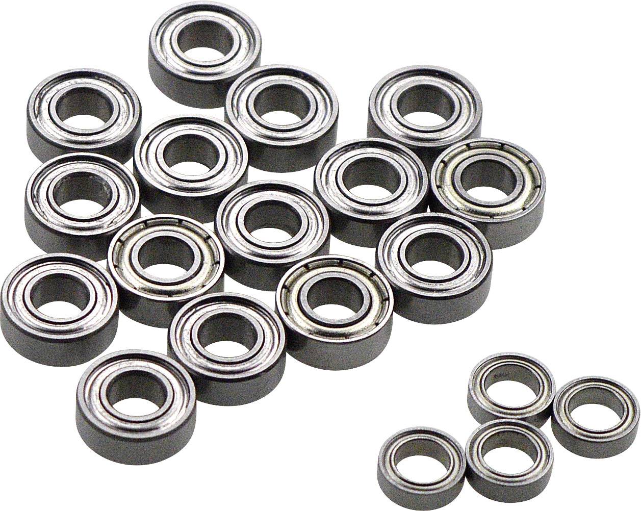 Several steel ball bearings of different sizes are lying on a white surface. They are arranged in a circular and silvery, gleaming pattern.