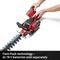A person is replacing the battery of a red hedge trimmer. Text in the image: 'Twin-Pack Technology - 2 x 18 V. Batteries sold separately'.