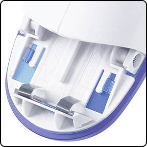 Close-up of an electrical device, probably an electric shaver, with blue and white plastic components, showing the underside with two rails.