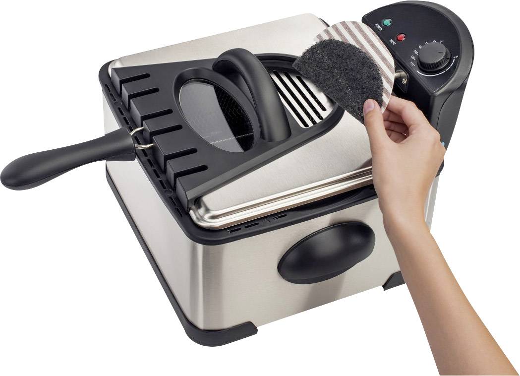 A person is cleaning the grease filter of an electric deep fat fryer with a sponge. The fryer is made of stainless steel, with the lid open.