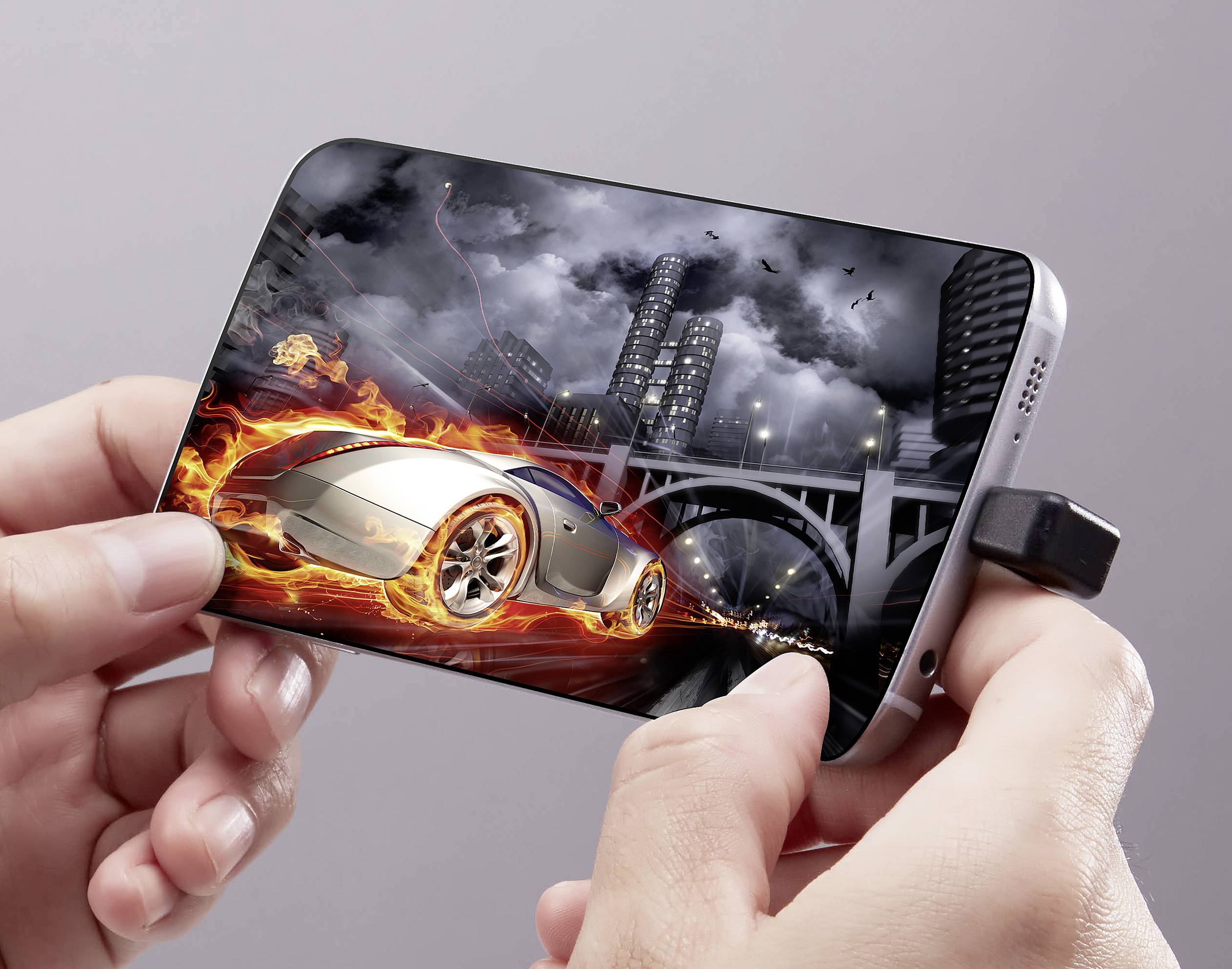 A hand is holding a smartphone displaying a video game with a burning racing car in an urban landscape.