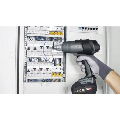 A person wearing gloves is holding a cordless drill while working on an open fuse box.