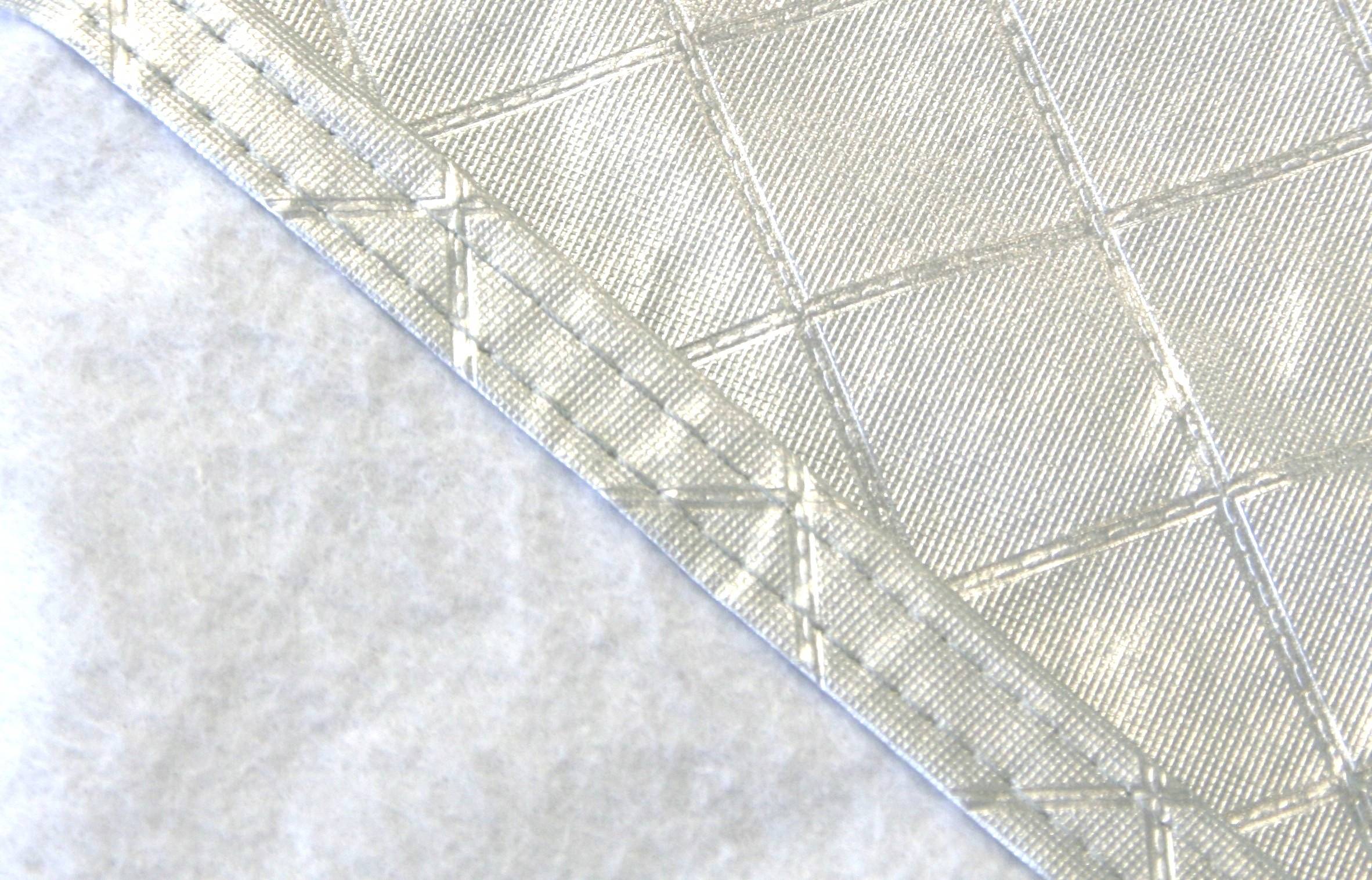 'A close-up of an angular piece of fabric with diagonal seams on a light, textured background.'