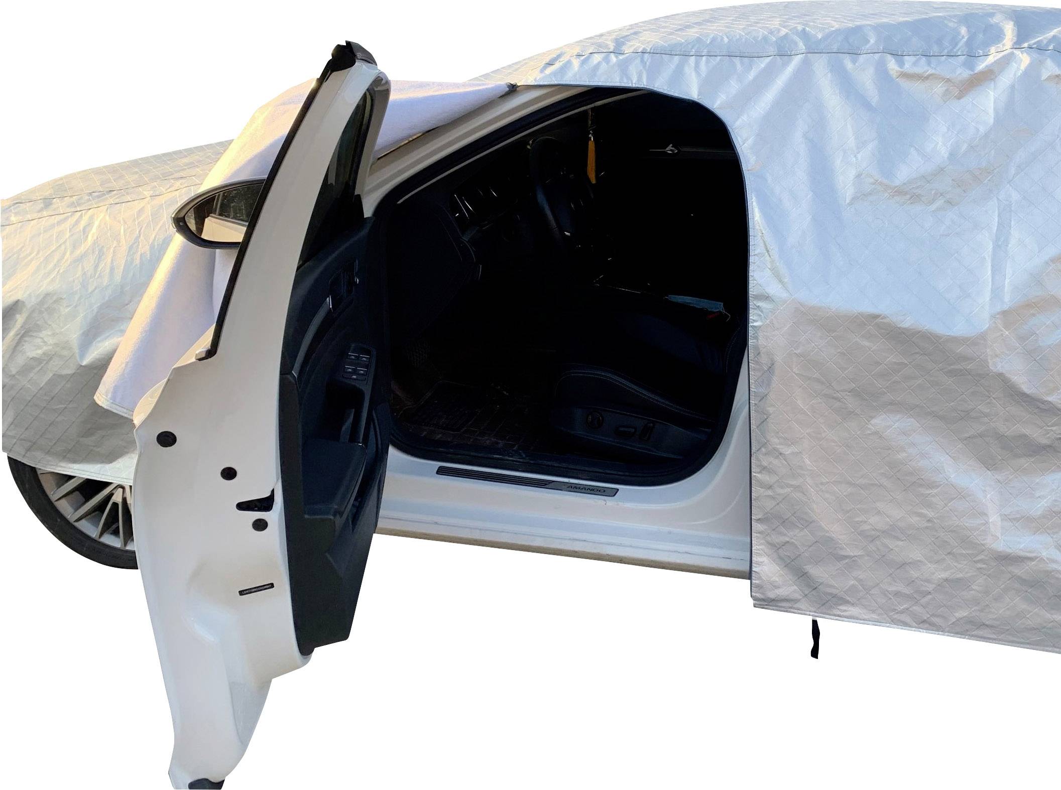 A car with an open driver's door is partially covered by a tarpaulin. The tarpaulin protects the vehicle from weather conditions.