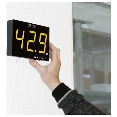 Hand holding a digital sound level meter mounted on a wall, displaying 42.9 dB.