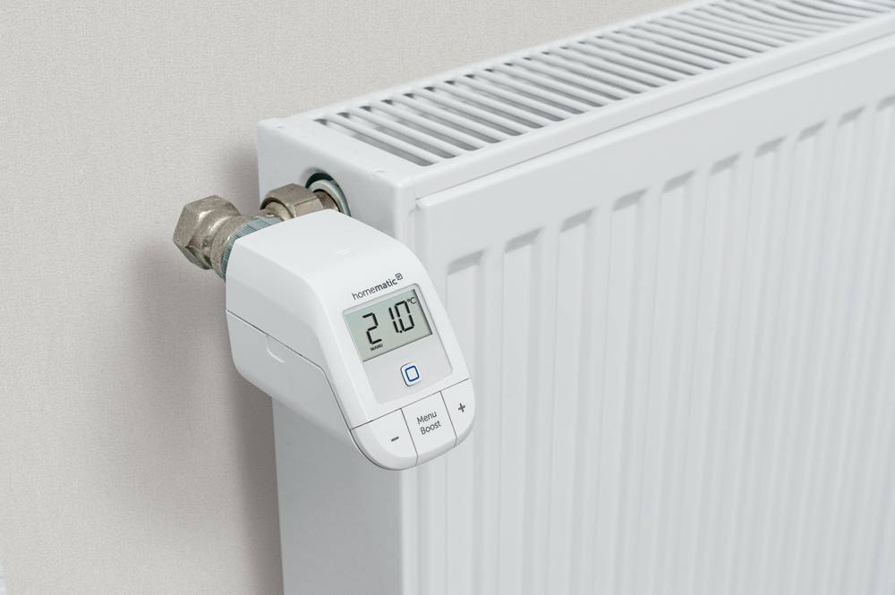 A radiator thermostat on a heating system shows the temperature reading of '21.0°C'. The device controls the heating output.