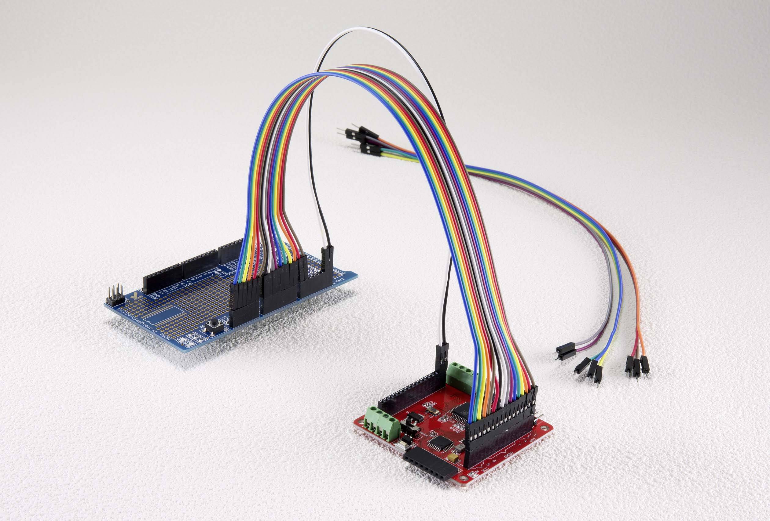 Two circuit boards with colourful cable connections. One blue and one red circuit board, each with numerous pins, interconnected by cables.