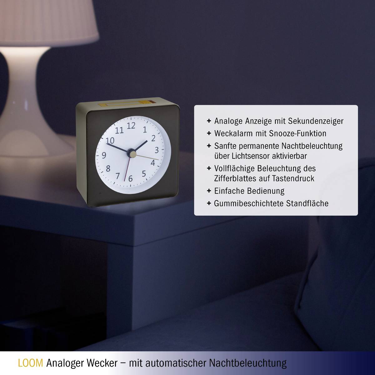 Analogue alarm clock with a round dial, illuminated face, showing 10:10; piece of furniture in the background, lampshade visible.