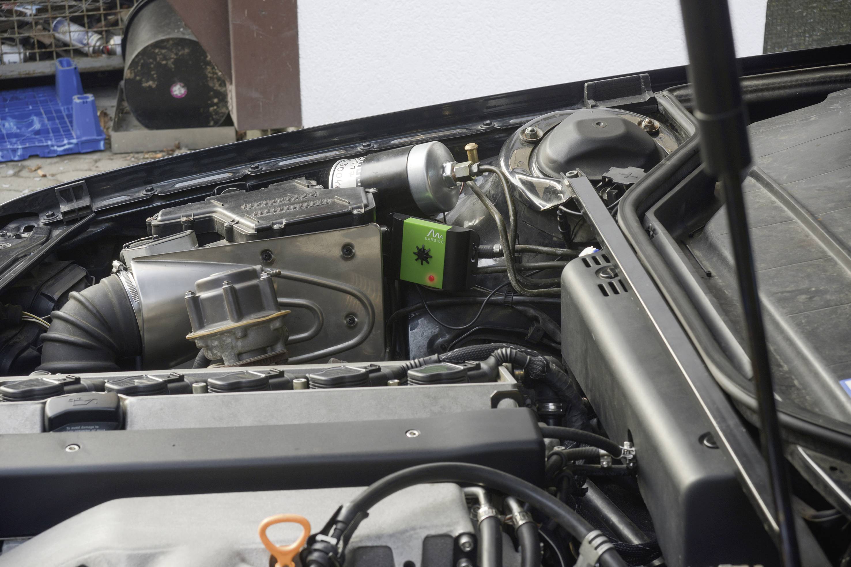 A car with an open bonnet reveals the engine compartment and components. Important detail: A green module with a star symbol.