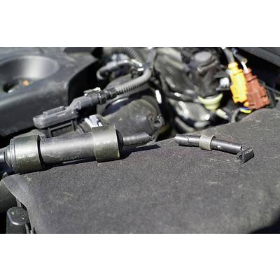 'Faulty ignition coils placed on an engine cover, with visible parts of the engine in the background.'
