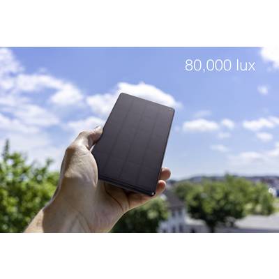 A hand holds a dark rectangular solar cell outdoors in bright sunlight; the text shows "80,000 lux", indicating high brightness.