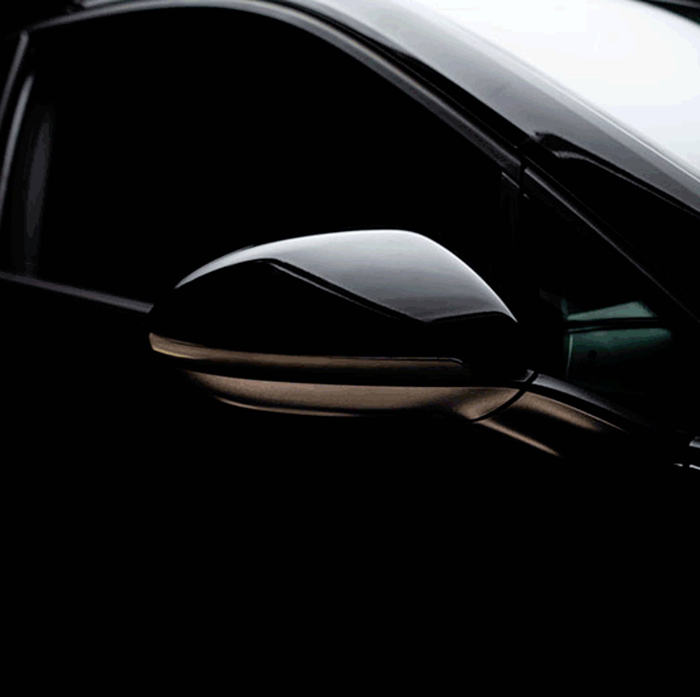 A black car wing mirror with a subtle light effect, set against a dark background, displays elegance and modernity.