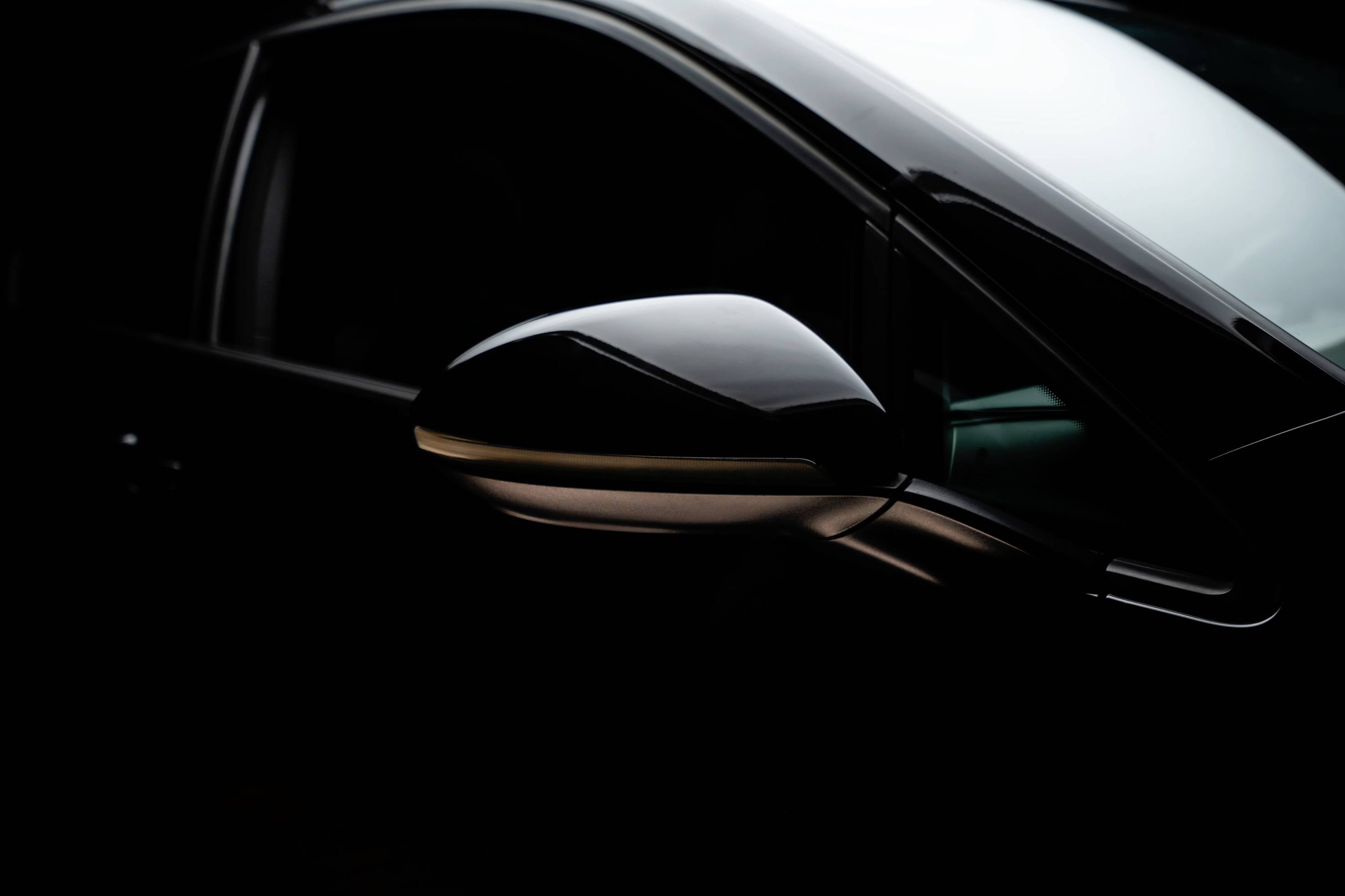 Car wing mirror and window frame in a dark environment, focusing on the clear lines and elegant design of the vehicle.
