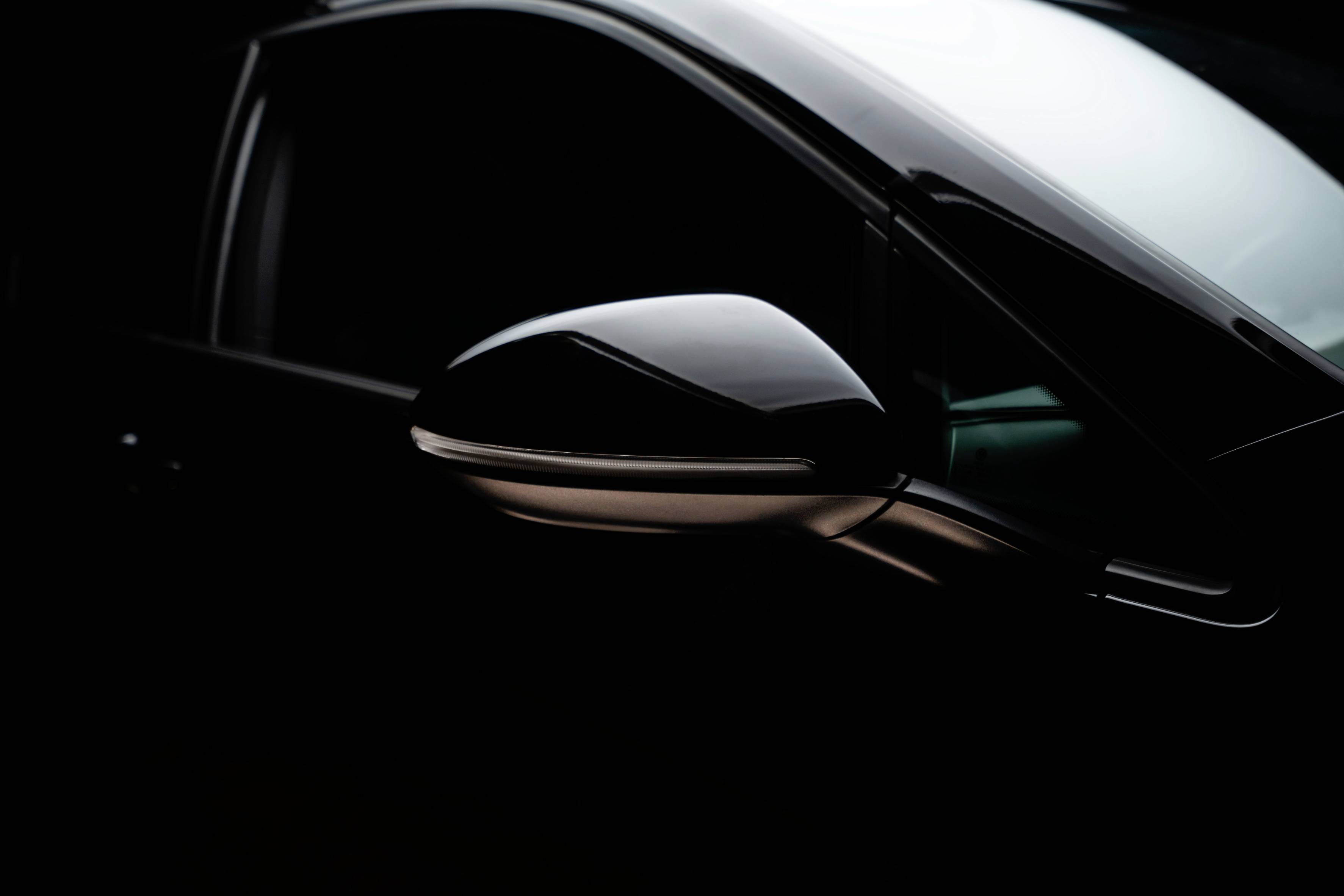 Black car in the half-light, focus on the aesthetically designed wing mirror.
