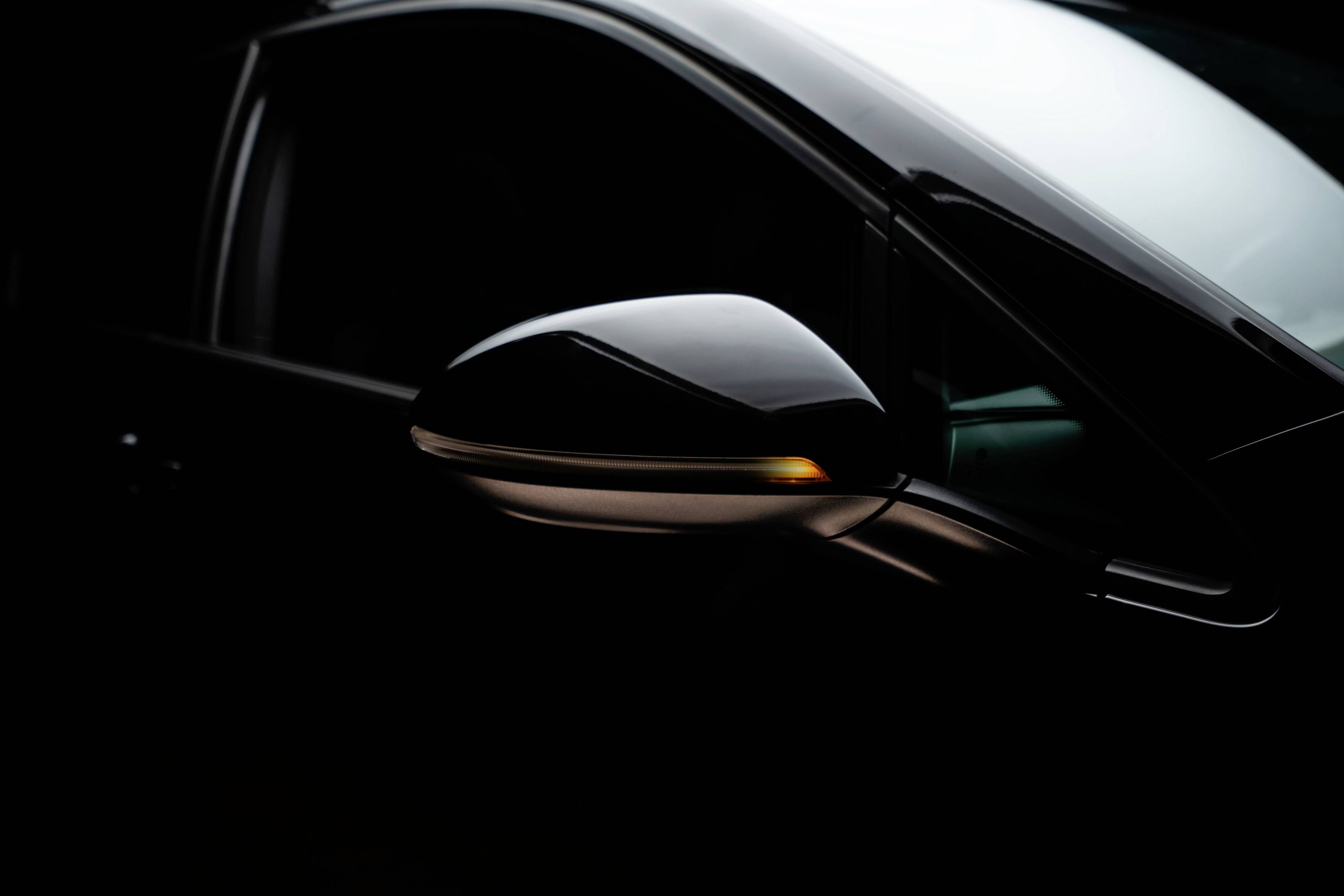 Close-up of a car showing the wing mirror. The mirror reflects soft light in a dark environment.