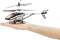 A small remote-controlled model helicopter is being held in a hand. The helicopter is black, white and orange.