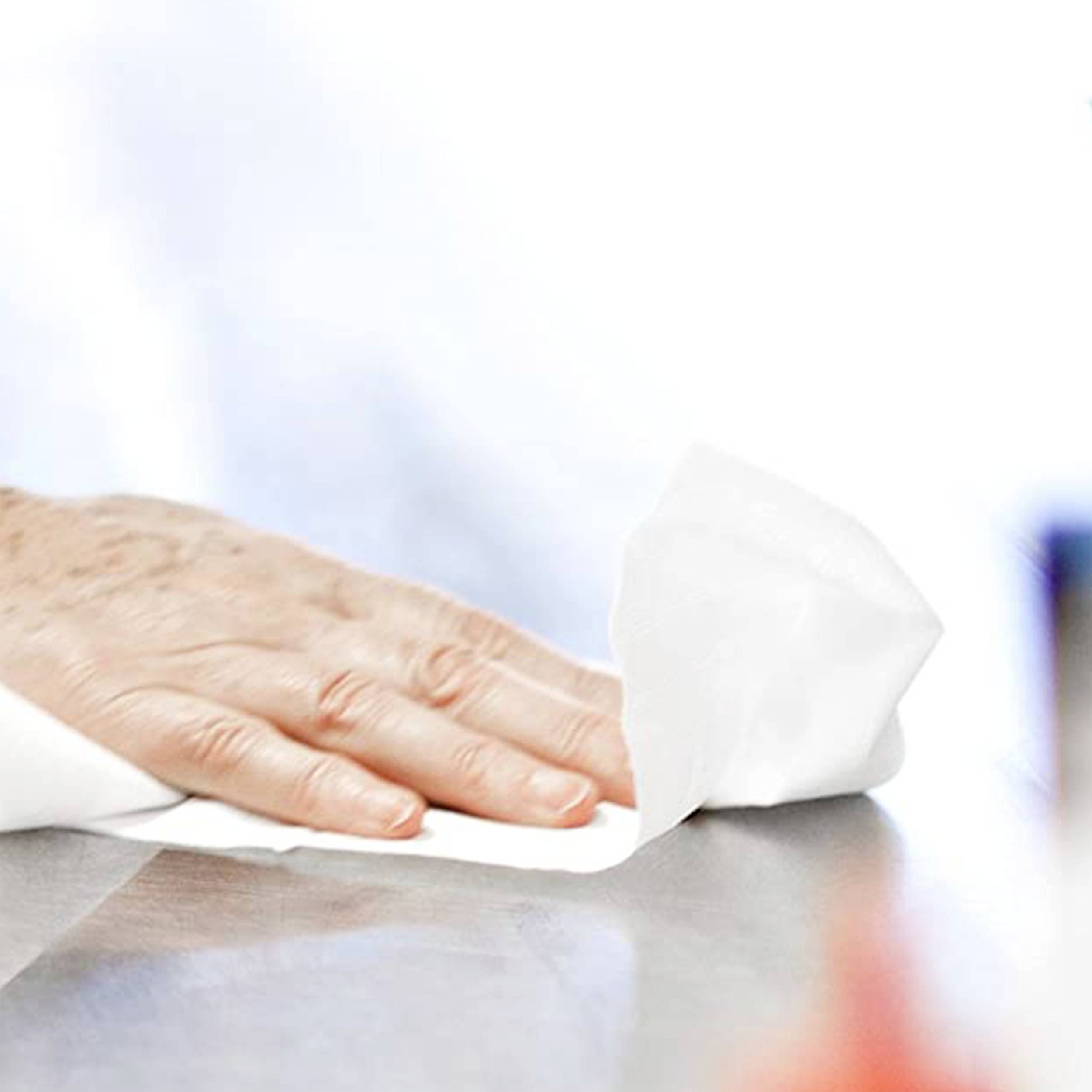 A hand wipes a shiny surface clean with a white disposable cloth.