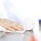 A hand wipes a shiny surface clean with a white disposable cloth.