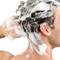 A man is washing his hair with foaming shampoo.