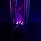 Purple spotlight beams through a metallic support frame in a dark room, creating light and shadow effects.
