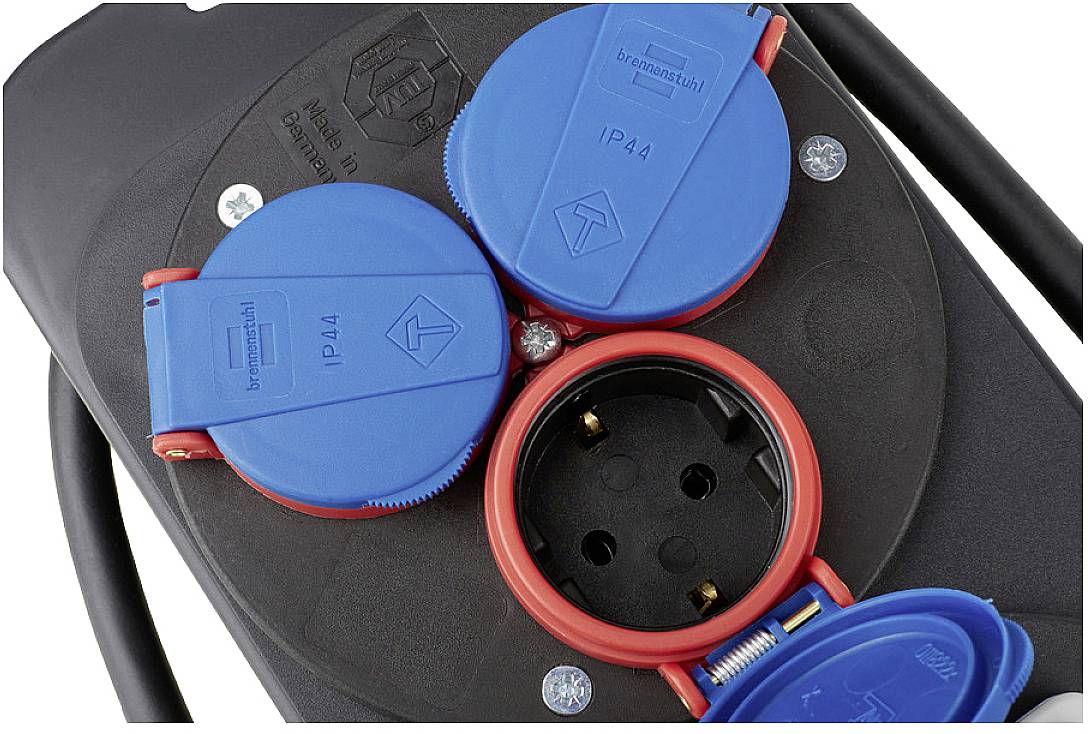 Close-up of three blue electrical sockets with red edges mounted on a black panel, in a typical industrial setting.