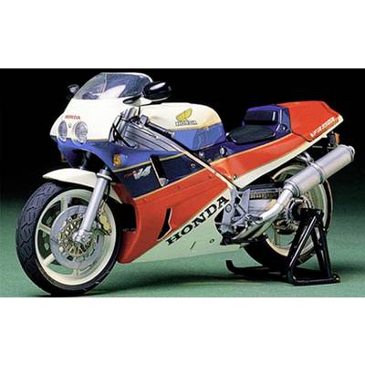 Honda motorcycle with sporty design, striking red, white and blue paintwork, stands against a green background.