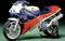 Honda motorcycle with sporty design, striking red, white and blue paintwork, stands against a green background.