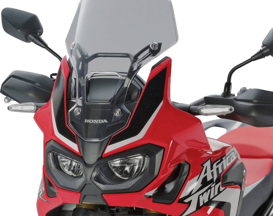 A red motorbike with an aggressive design and protective shield, brand 'Honda Africa Twin', photographed from the front.