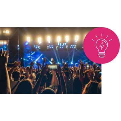 Crowd raising hands at a concert with an illuminated stage. Light bulb symbol in the top right indicating an idea.