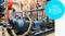 An engineer wearing a hard hat and carrying a tablet is inspecting an industrial facility with several blue pumps. A pump symbol is prominent in the foreground.