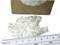 'White, crystalline flakes beside a ruler and a cardboard container.'