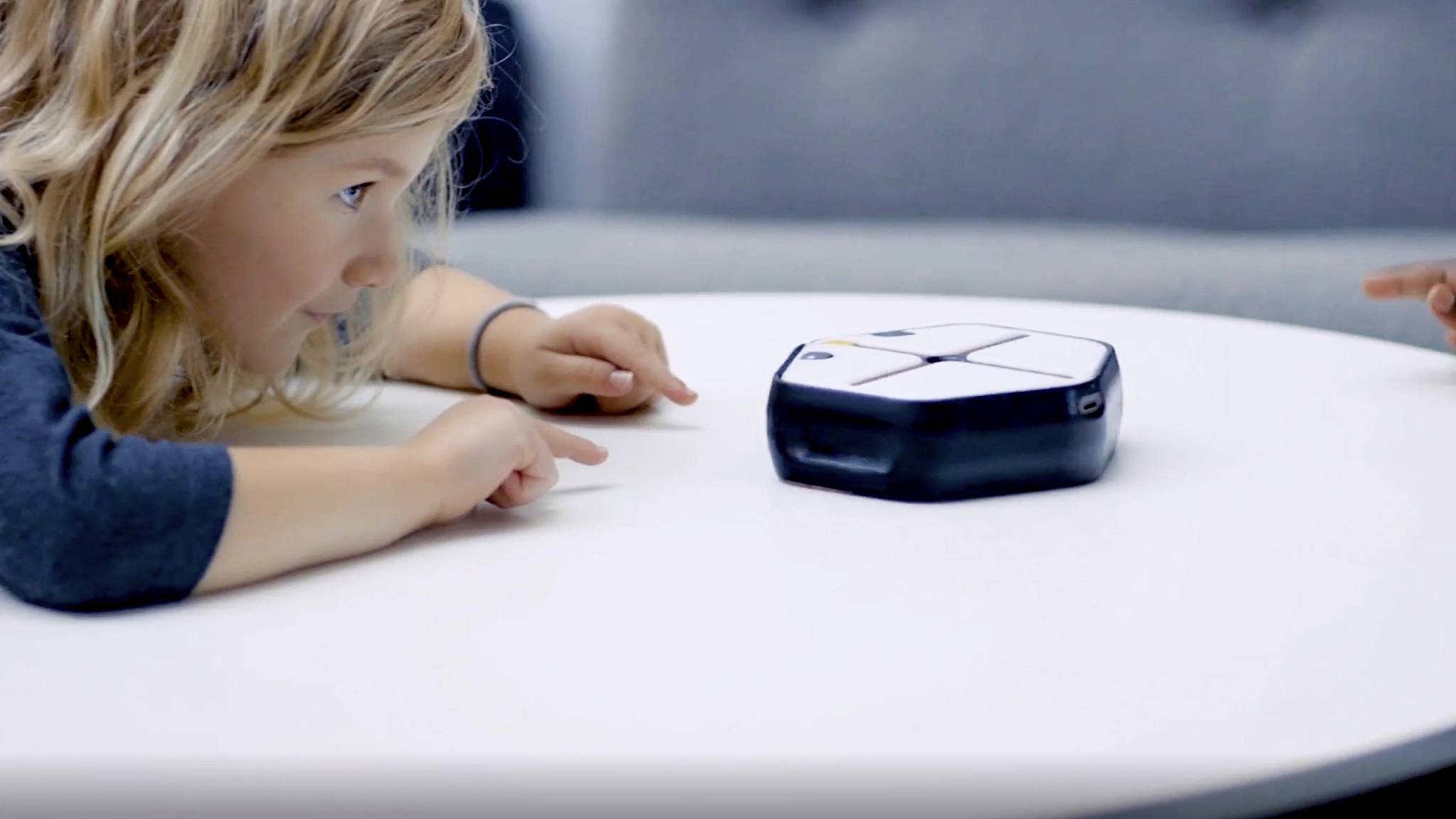 A child is playing intently with a touch-activated electronic device on a table.