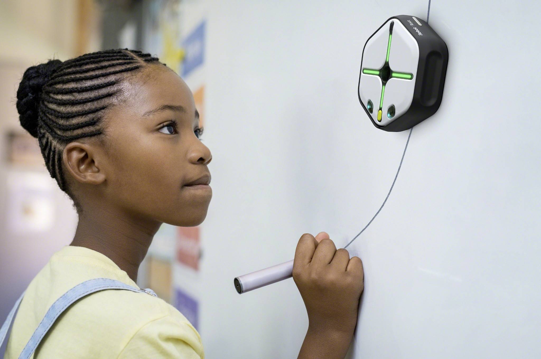 A child is using a technical device on a board that uses a kind of digital pen for interaction.