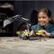 A girl is playing with a construction kit excavator on a table. She is smiling and looking concentratedly at the toy.