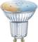 Halogen light bulb with GU10 base, upper surface showing blue and orange tones, symbolising energy efficiency and light variations.
