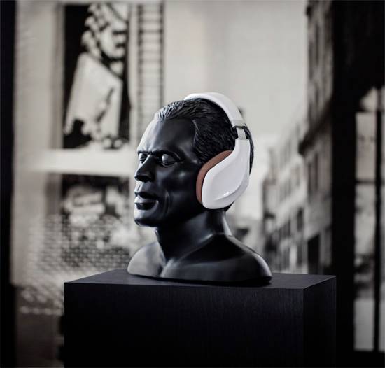 Bust of a man wearing headphones on a plinth, with an urban background.