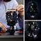 A person is assembling a black helmet model using Lego bricks. On the right, a completed model, inspired by a famous science fiction character.