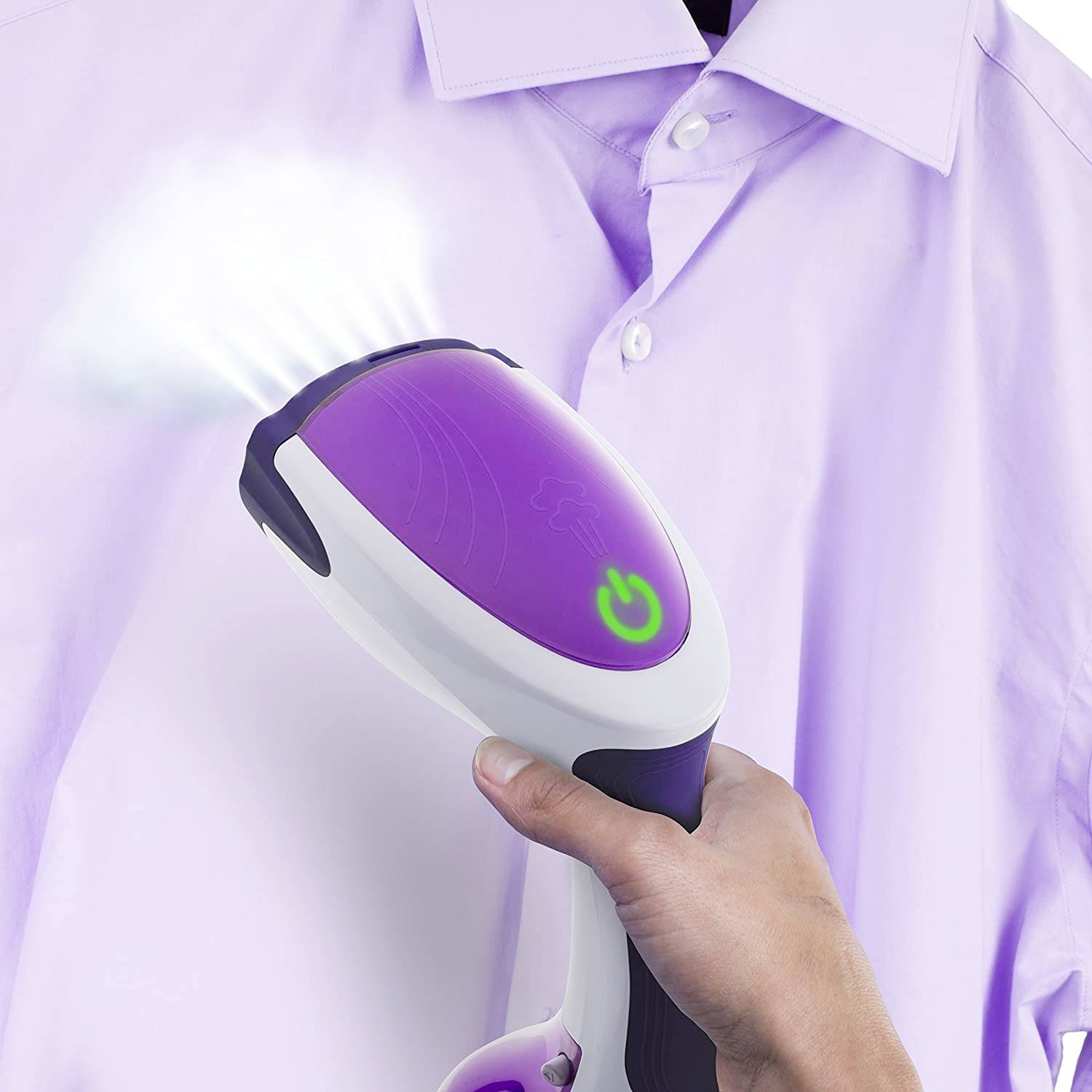 A hand is using a steam iron to smooth out a purple shirt. Steam is emerging from the device, which is positioned near the shoulder.