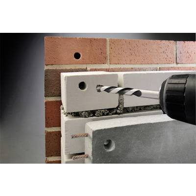 A drill is inserted into a concrete slab with a brick facade to create a hole. The scene depicts the drilling process in detail.