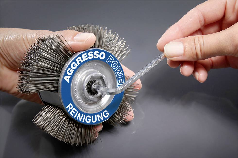 'Agresso Power Cleaning' Metal element is held and processed with a spanner. Hands are fixing and manipulating the object.