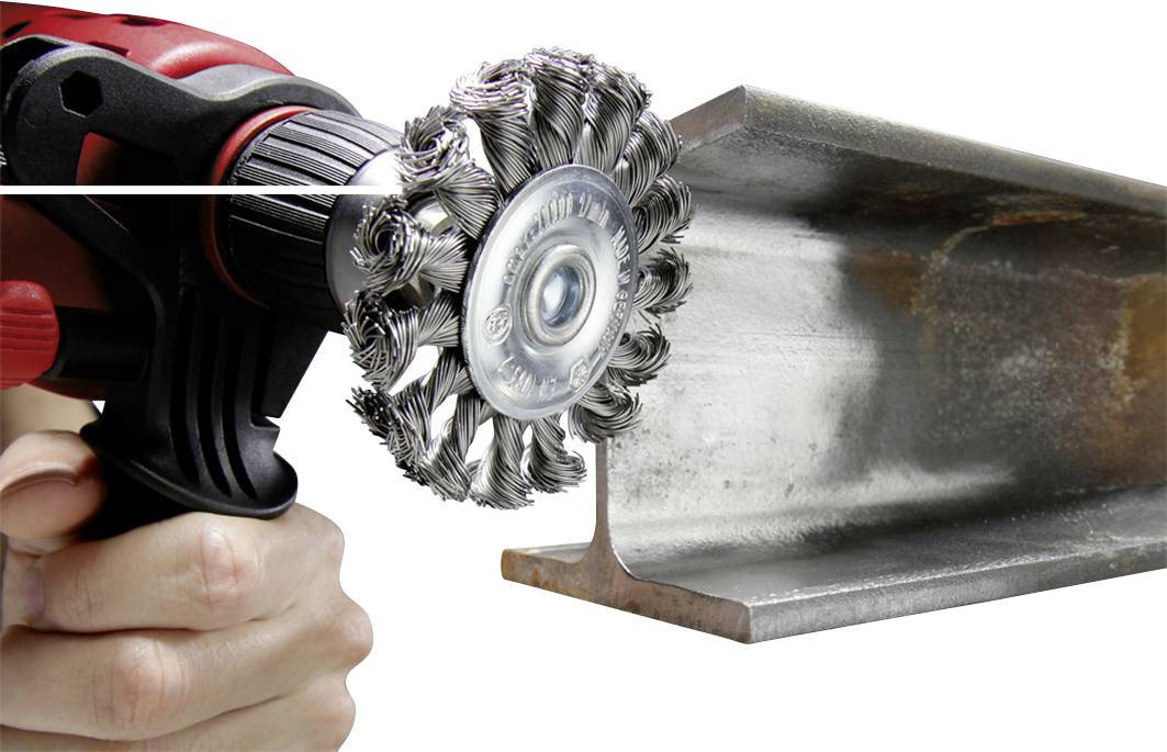 A hand is holding a drill with a wire brush attachment, which is being used to clean a metal support.