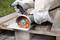 A person is cutting a tile with an angle grinder on a wooden palette. Protective clothing and gloves are being worn.