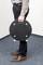 A person is standing on carpet and holding a round, black plate with a handle. The plate has four silver screws.