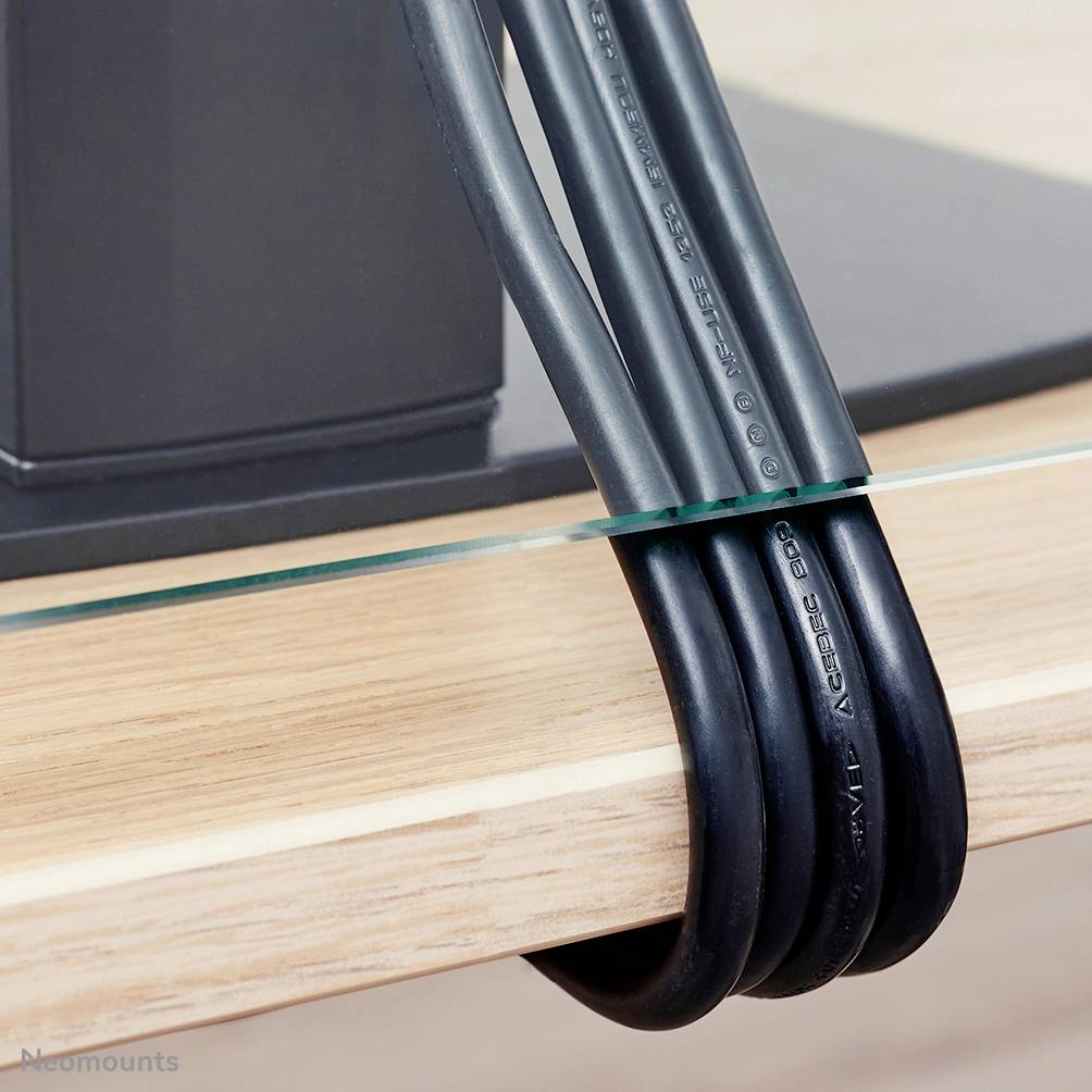 Black cables are neatly bundled along the edge of a piece of furniture. Cable management is being demonstrated.