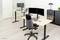 Two modern workstations with height-adjustable desks, monitors, keyboards and office chairs in a bright office.