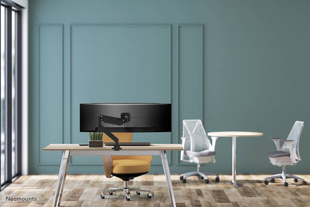 Modern office chair and desk with a large screen in a stylish, minimalist room with a green wall background.