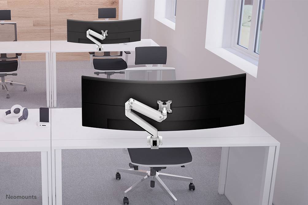 Two modern offices with large, curved monitors on white desks in front of bright windows. Monitor arms are flexibly adjustable.