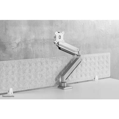 Ergonomic aluminium monitor arm, clamped to the edge of a desk, adjustable in height and angle, positioned in front of a concrete wall.