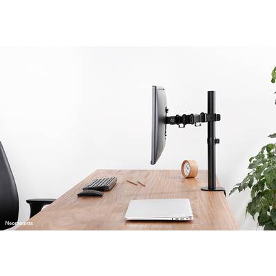 Monitor arm on a desk, holding a screen. Laptop, keyboard, mouse, clock and plants in the background.
